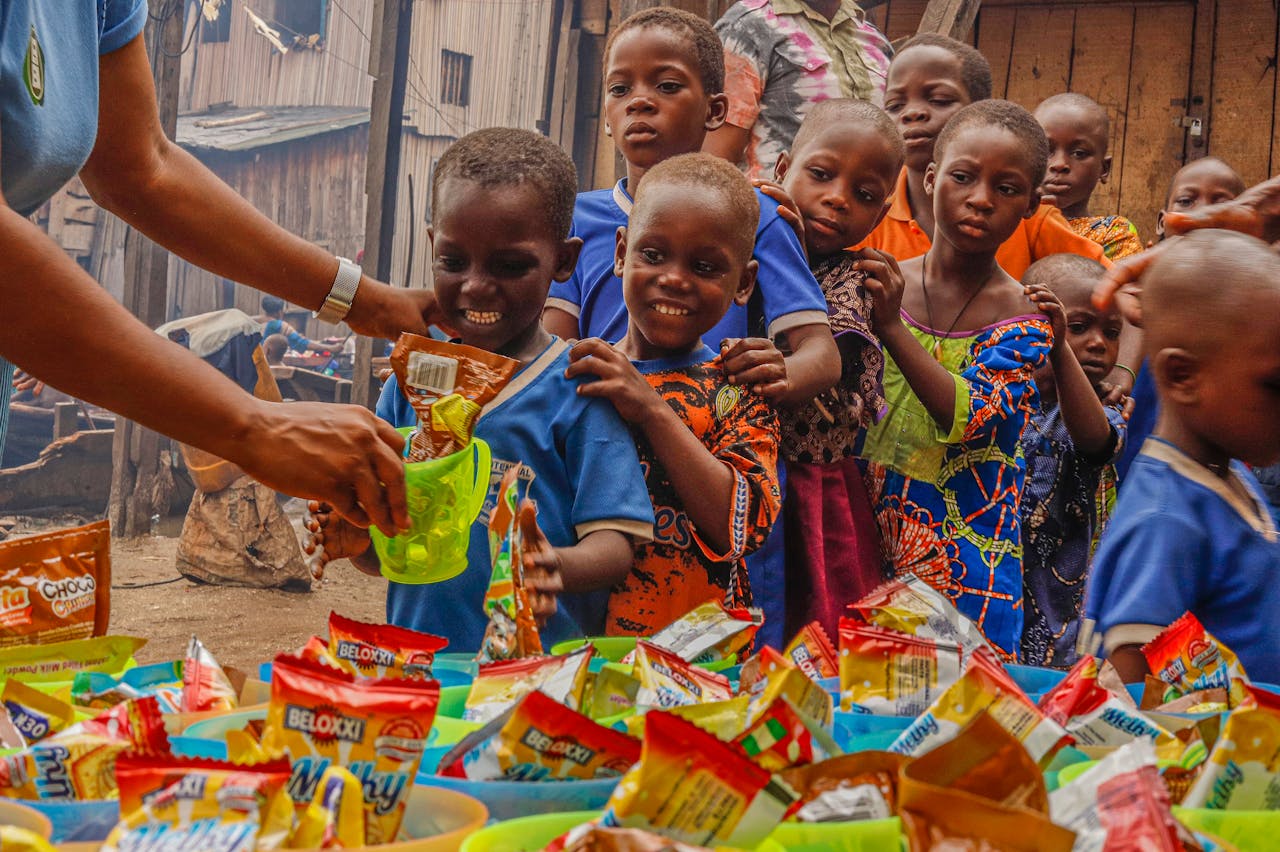 Joyful children receiving food supplies from a volunteer in an outdoor setting.