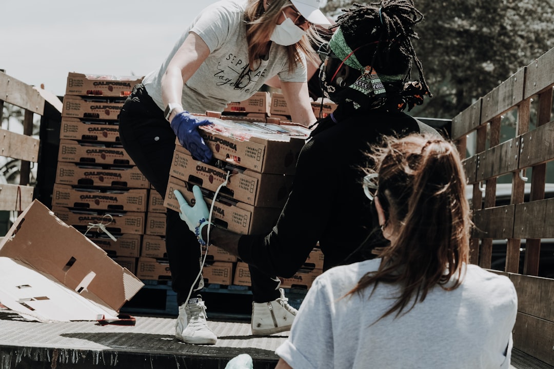 woman-in-white-t-shirt-and-blue-denim-jeans-sitting-on-brown-cardboard-box-a4ax1apccfa